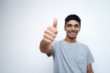 Photo of young guy 20s posing isolated on pastel white wall background studio portrait. People sincere emotions lifestyle concept. Mock up copy space. Showing thumbs up.