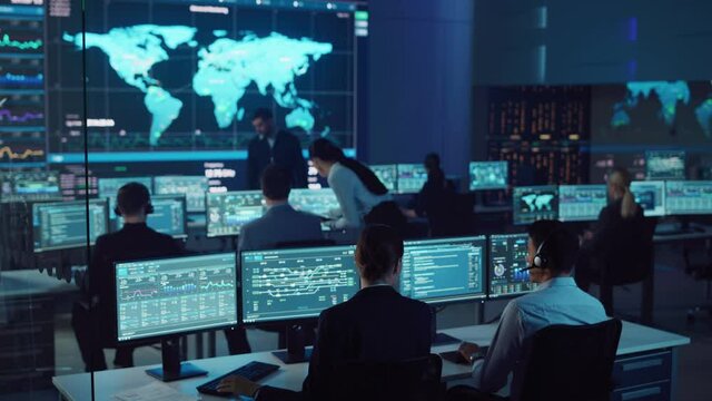 Team of Professional Computer Data Science Engineers Work on Desktops with Screens Showing Charts, Graphs, Infographics, Technical Neural Data and Statistics. Dark Control and Monitoring Room.