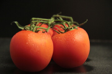 red, fresh and organic tomatoes on a black background