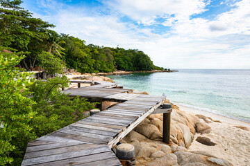 Wooden pathway built on a rocky coast  at Koh Munnork island , Rayong, Thailand.