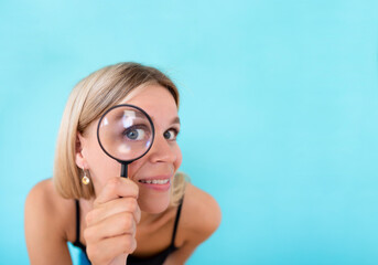 Private data and spying mockup. Curious young woman looking through a magnifying glass on color background. Copy space