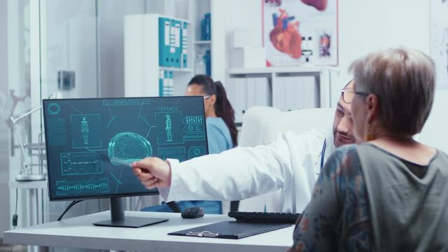 Young doctor analyzing brain damages on futuristic medical scan with elderly patient. Practitioner explayning medicine computer diagnosis image X Ray. Radiology health care scan analyzing in modern