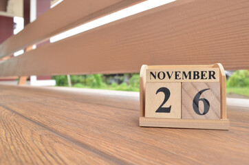 November 26, Number cube with wooden balcony background.