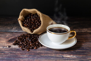 
Hot coffee in a mug and coffee beans roasted on the wooden floor