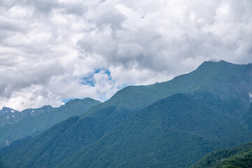 High green mountains with snowy peaks in clouds and fog