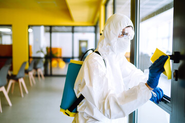 Man in a protective suit washes an office to prevent COVID-19. Cleaning and disinfection office...