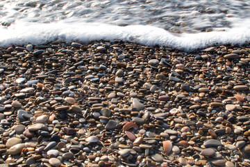 shiny pebbles from the beach with a wave on top. Background. Textures