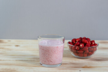 Milk shake smoothie of wild strawberry in glass on wooden table