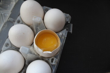 preparing Breakfast omelets scrambled eggs pancakes eggs white chicken lie in the grill one egg is broken and a bright yellow yolk is visible on a gray stone black background and a place to insert tex