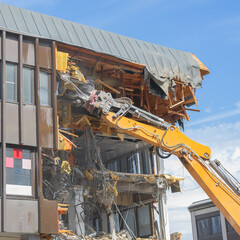 Fototapeta premium Demolition excavator tearing down a building in Kuopio, Finland