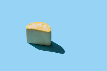 One tasty marshmallow with hard shadows on a blue background with copy space