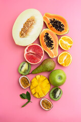 Summer abstract background with mix of various exotic fruits. Pink background. Flat lay.