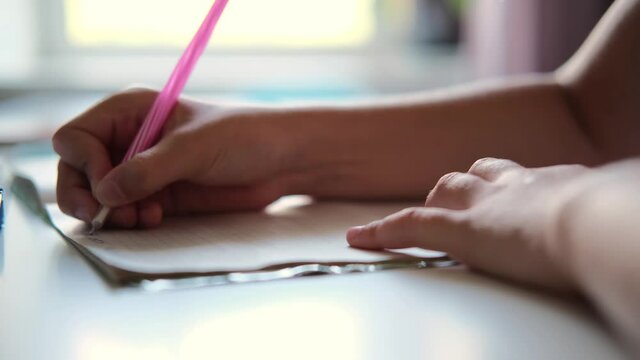 A male hands writing on a piece of paper. Writing essay or letters. A schoolboy writes in a notebook. Doing homework.