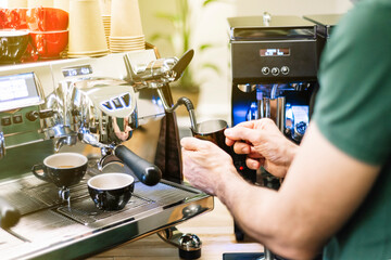 Barista warming up milk with industrial coffee maker
