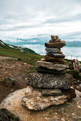 Pile of stones on the hill with view to the Tromso area, northern Norway. Fiord with mountains and sea in the background. Climbing mountain.