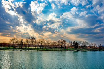 Naklejka premium Water reservoir with a blue sky and leafless trees
