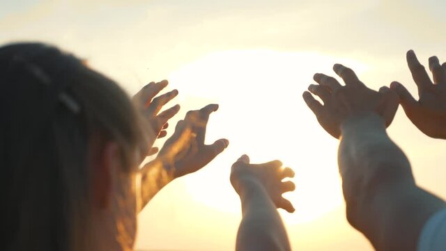 People's hands reach for the sun at sunset. Happy family together. Teamwork. A cry for help, People together in prayer turn to the sun.