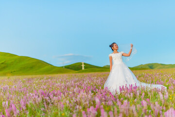 The woman in the wedding dress is in the prairie.