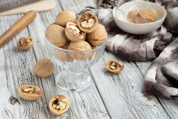 Fototapeta na wymiar closed and split walnuts in dishes on a light wooden background, textiles, cutting Board