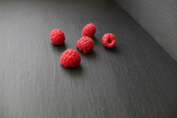 food background red raspberries are scattered lying on a gray stone black background there is a place to insert text