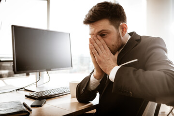 Business crisis concept. Emotional young businessman at work. Worried stressed manager sitting at...