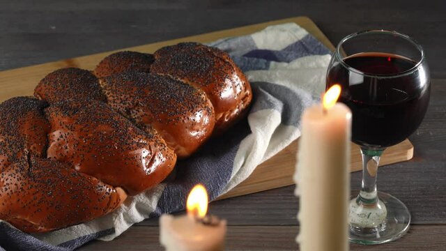 Shabbat Shalom. Challah bread, shabbat wine and candles on wooden table.