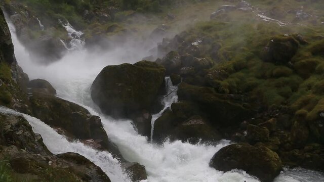 View to Kleivafossen waterfall on Briksdalselva river, Briksdalsbreen glacier, Norway. Waterfall on the way to Briksdal or Briksdalsbreen glacier in Olden, Norway and green mountains, close up.