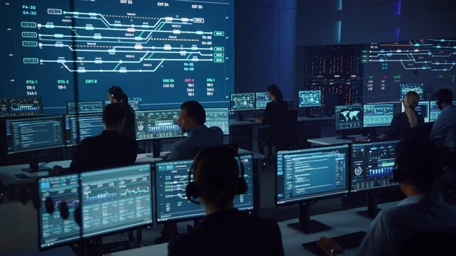Team of Professional Computer Data Science Engineers Work on Desktops with Screens Showing Charts, Graphs, Infographics, Technical Neural Data and Statistics. Low Key Control and Monitoring Room.