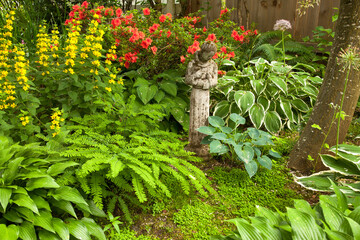 A garden statue of Saint Francis of Assisi holding a bird, in a flower garden in Salem, Oregon