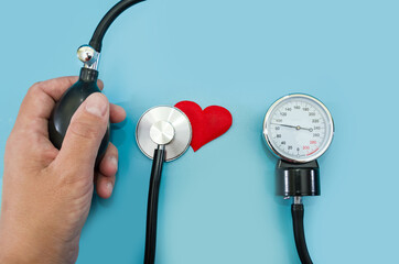 female hand, tonometer, stethoscope and heart on a blue background. The concept of health, the...
