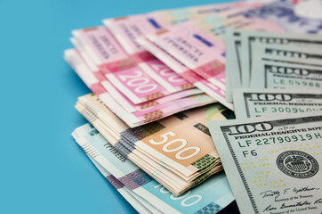 Obraz na płótnie Canvas Dollars and hryvnias on a blue background. Much money. Close-up.