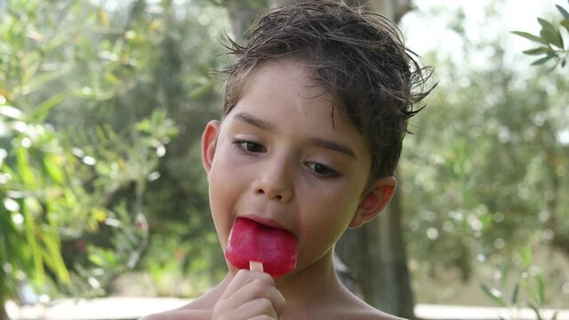 Video in 4k di un bambino biondo che si mangia un gelato nel giardino a casa