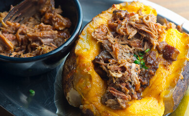 Baked potato. BBQ or steakhouse side dish favorite. Potato with butter, cheddar cheese, sour cream, chives, bacon, brisket and green onions. Classic American or BBQ restaurant favorite.