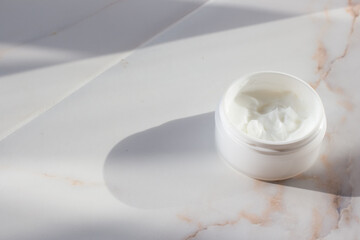 Face mask in a white jar on a marble table. Spa concept. Minimalism.
