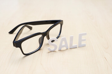 Block letters on Sale with eyeglasses on the wooden table 