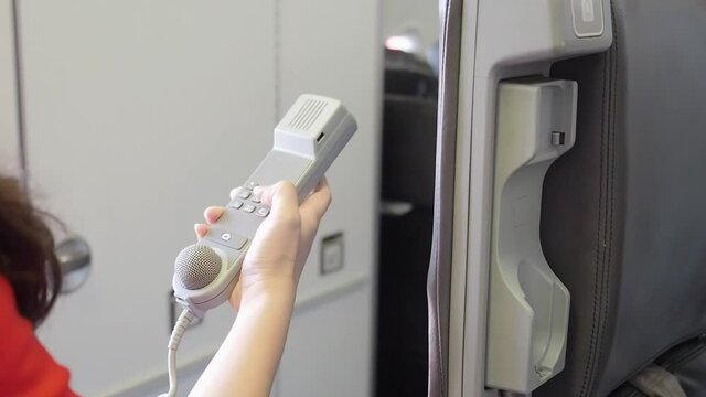 female cabin crew pick up interphone and make emergency call in flight. Aircraft equipment. 