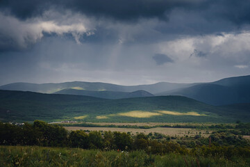 Naklejka premium Picturesque green valley among the mountains before a storm.