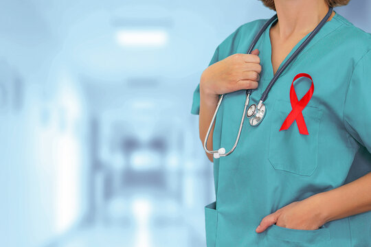 Female surgeon with stethoscope with red ribbon HIV standing on blurred background of corridor clinic.