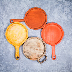 Set of four hand carved wooden serving boards arranged on gray table. Top view flat lay.
