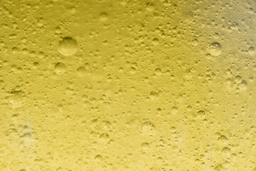 Close-up macro fullscreen with shallow depth of field of bubbles inside a yellow liquid. Graphic design.