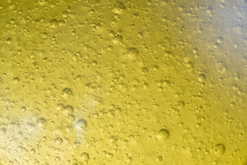 Close-up macro fullscreen with shallow depth of field of bubbles inside a yellow liquid. Graphic design.