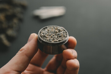 Close up of marijuana blunt with grinder. Rolling a marijuana joint. Cannabis use concept.
