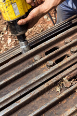 Man hands with tool tightening screw on metal track of tractor under maintenance