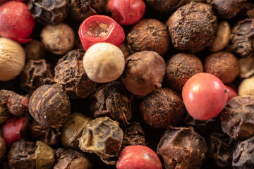 Fullscreen macro closeup with shallow depth of field of unmilled red, green, white and black peppercorns