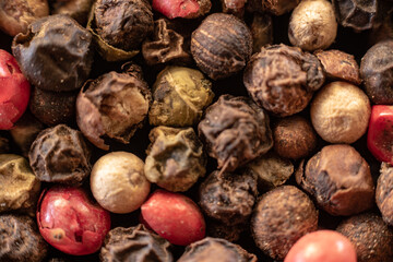 Fullscreen macro closeup with shallow depth of field of unmilled red, green, white and black peppercorns