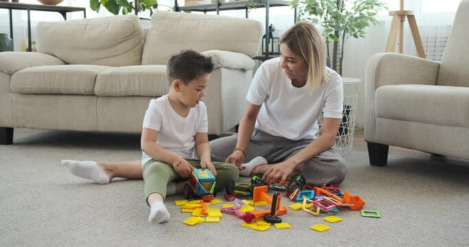 Mother and son having fun assembling toy car at home