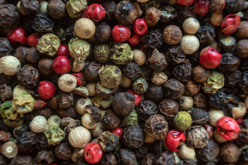 Fullscreen macro closeup with shallow depth of field of unmilled red, green, white and black peppercorns