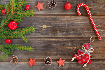 New year flat lay: Christmas green spruce branch with red sugar snow apples, candy cane, cones, red stars, linen new year tree on a rustic wooden background