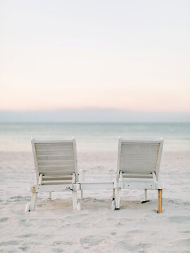 Wooden chairs on beach at sunset