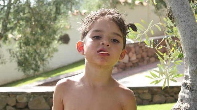 Video in 4k di un bambino biondo che si mangia un gelato nel giardino a casa
